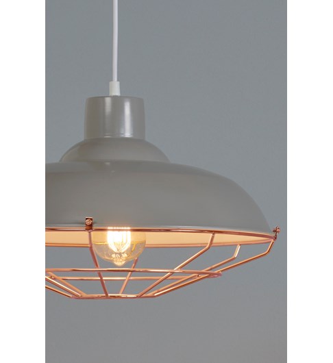 A close up shot of a grey painted metal lampshade with a copper coloured thin metal cage surrounding an illuminated bulb. The fitting is taken against a pale grey background.